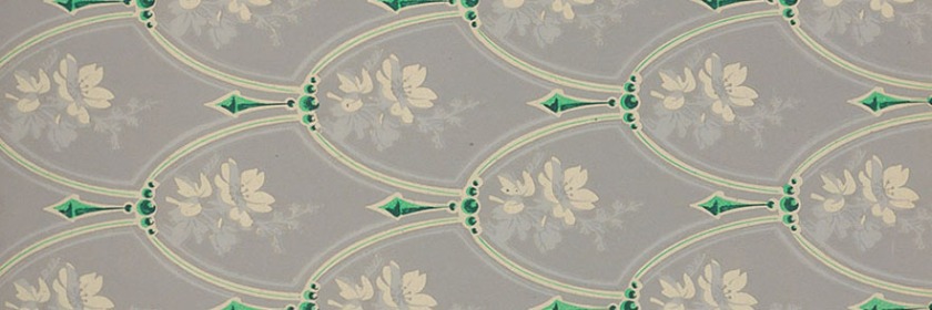 A shield type pattern with green pendants and white flowers on a grey background.